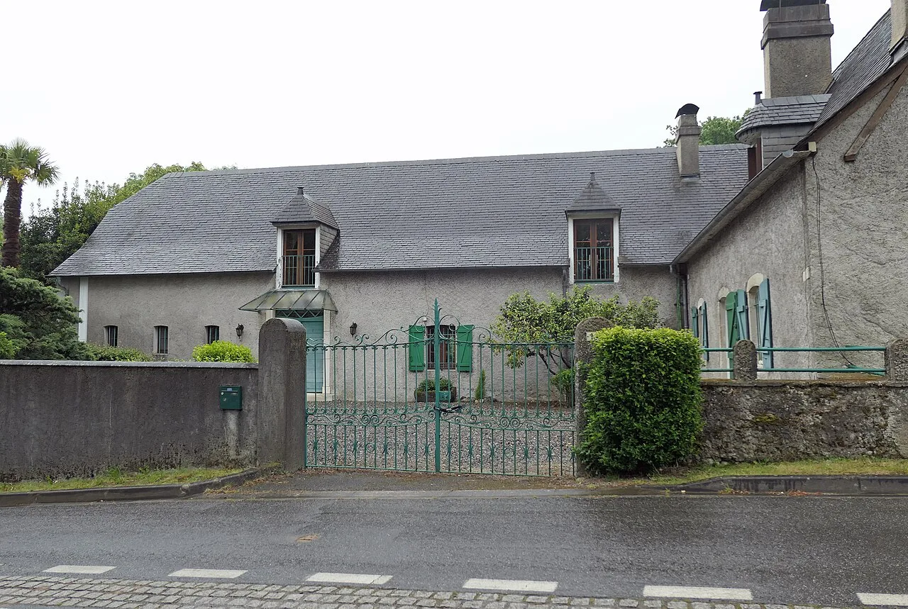 maison en pierre grise couverte en ardoise, volets vert vif, lucarnes sur le toit